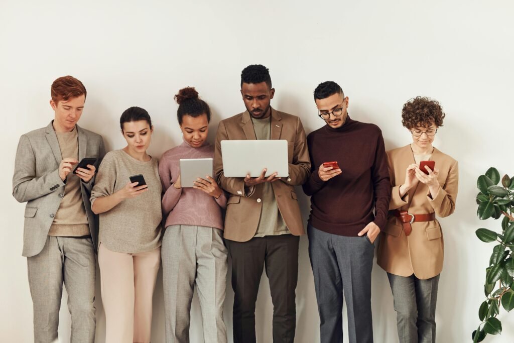 A diverse group of adults interacting with various devices in a stylish office setting, showcasing the many ways of contacting Havesites, a website design service near them for a free website qoute from a friendly website designer.